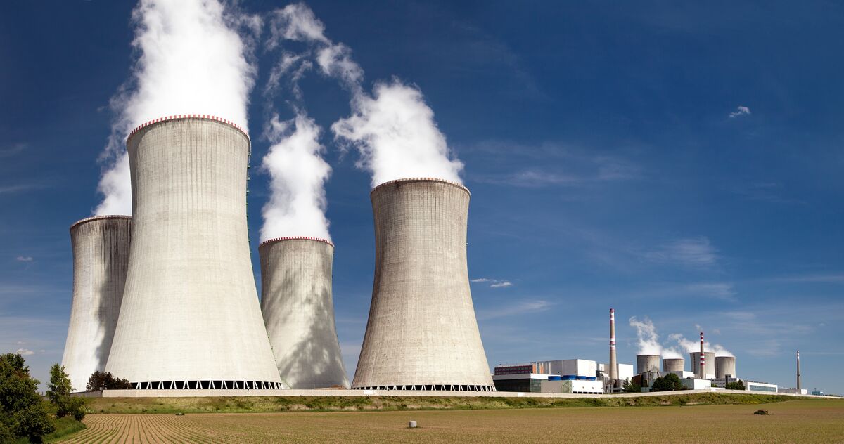 Nuclear power plant with cooling towers generating steam against a blue sky